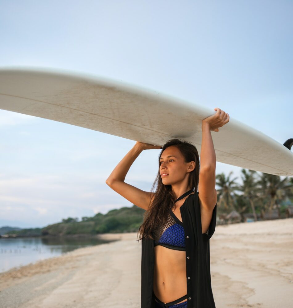pretty sporty girl or woman in shape going to surf