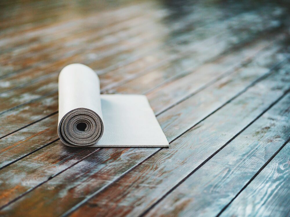 rolled yoga mat on wooden deck background. Fitness and health. Exercise equipment. Yoga and pilates.